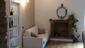 A cozy living room with a white sofa, a fireplace, and a bookshelf. - Bergamo: House with character (Bergamo)