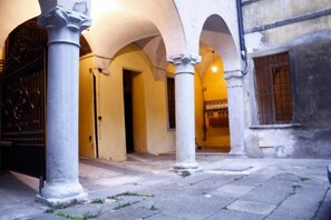 An interior courtyard with arches and columns, a door, and a window with barred shutters. - Bergamo: House with character (Bergamo)