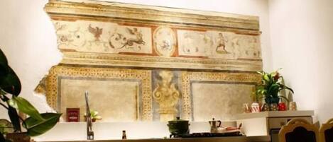A kitchen with a marble countertop, wooden cabinets, and a decorative wall with a mosaic.