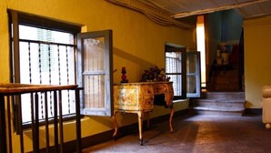 A hallway with a wooden railing, a vintage-style table with a vase, and a staircase leading to another room. - Bergamo: House with character (Bergamo)