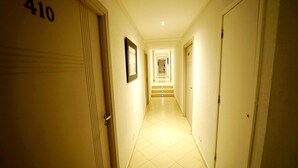 Pasillo de hotel con puerta número 410, un cuadro en la pared y una escalera que sube a otro piso.