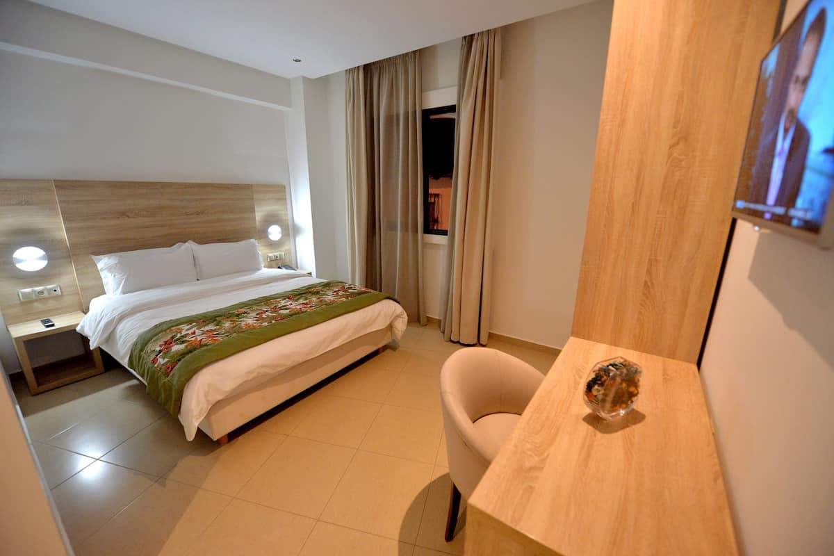 A hotel room with a bed, a nightstand, a desk, a chair, and a television.
