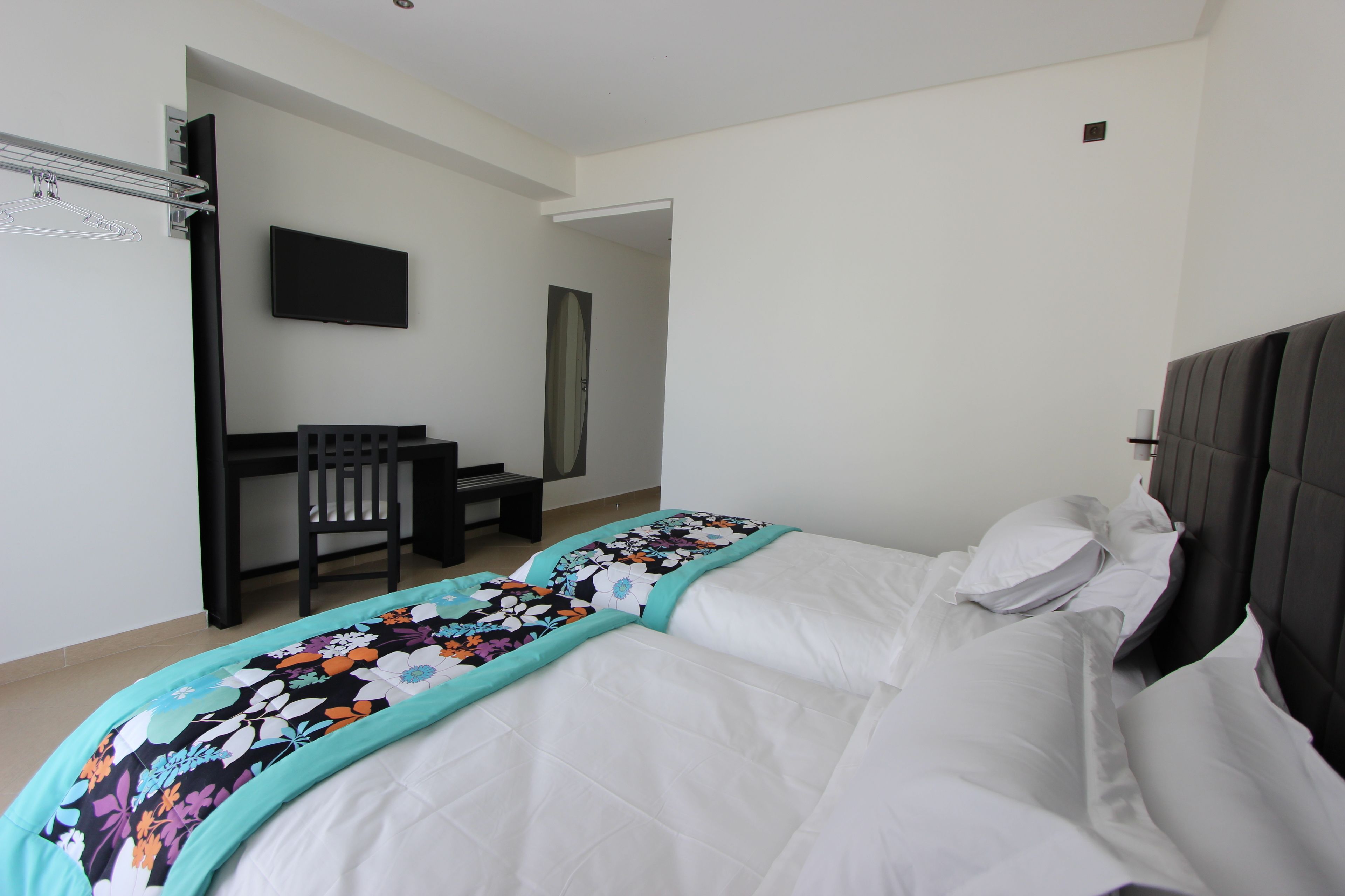 Un dormitorio con cama, escritorio y televisor.
