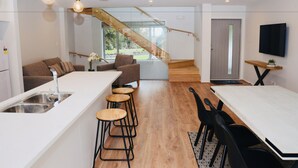 A modern kitchen with a central island, bar stools, and a dining table with chairs.