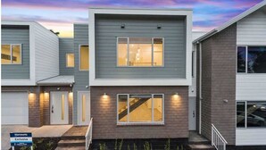 A modern multi-story residential building with a garage, a staircase, and a well-lit entrance.