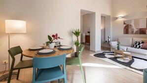 A modern living room with a dining area, a sofa, a coffee table, and a lamp. - Apartments Florence - Alfani Terrace (Firenze)