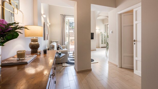 A hallway with a wooden floor, a sofa, a lamp, and a door. - Apartments Florence - Alfani Terrace (Firenze)