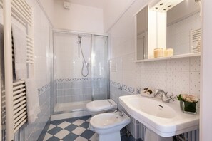 Une salle de bain équipée d’une douche, de toilettes, d’un bidet et d’un lavabo.