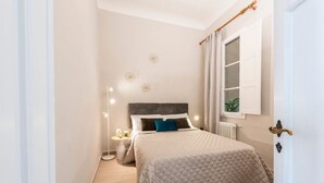 A bedroom with a bed, bedside lamps, a window with curtains, and a radiator. - Apartments Florence - Alfani Terrace (Firenze)