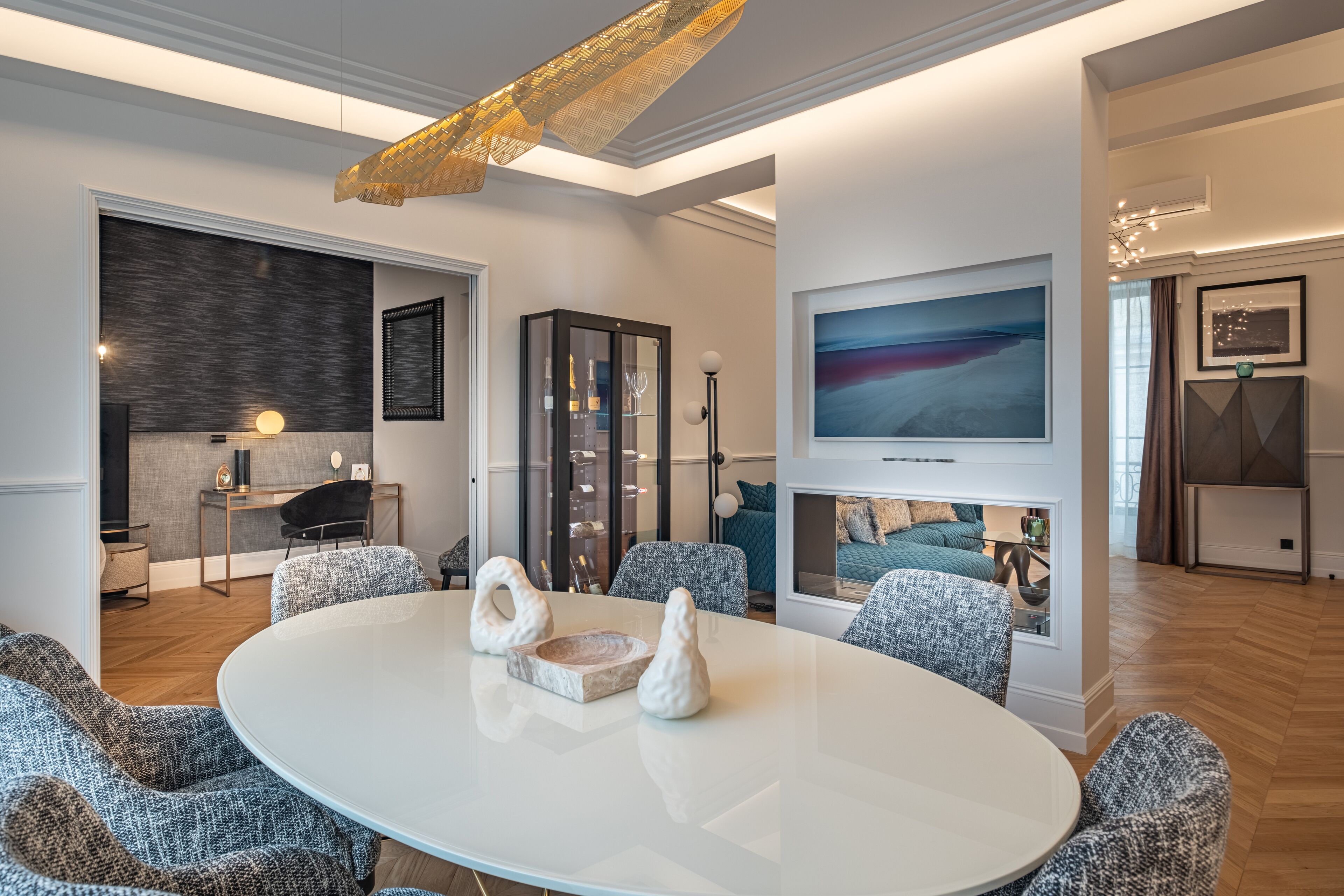 A modern living room with a round table, comfortable seating, a fireplace, and a large painting on the wall.