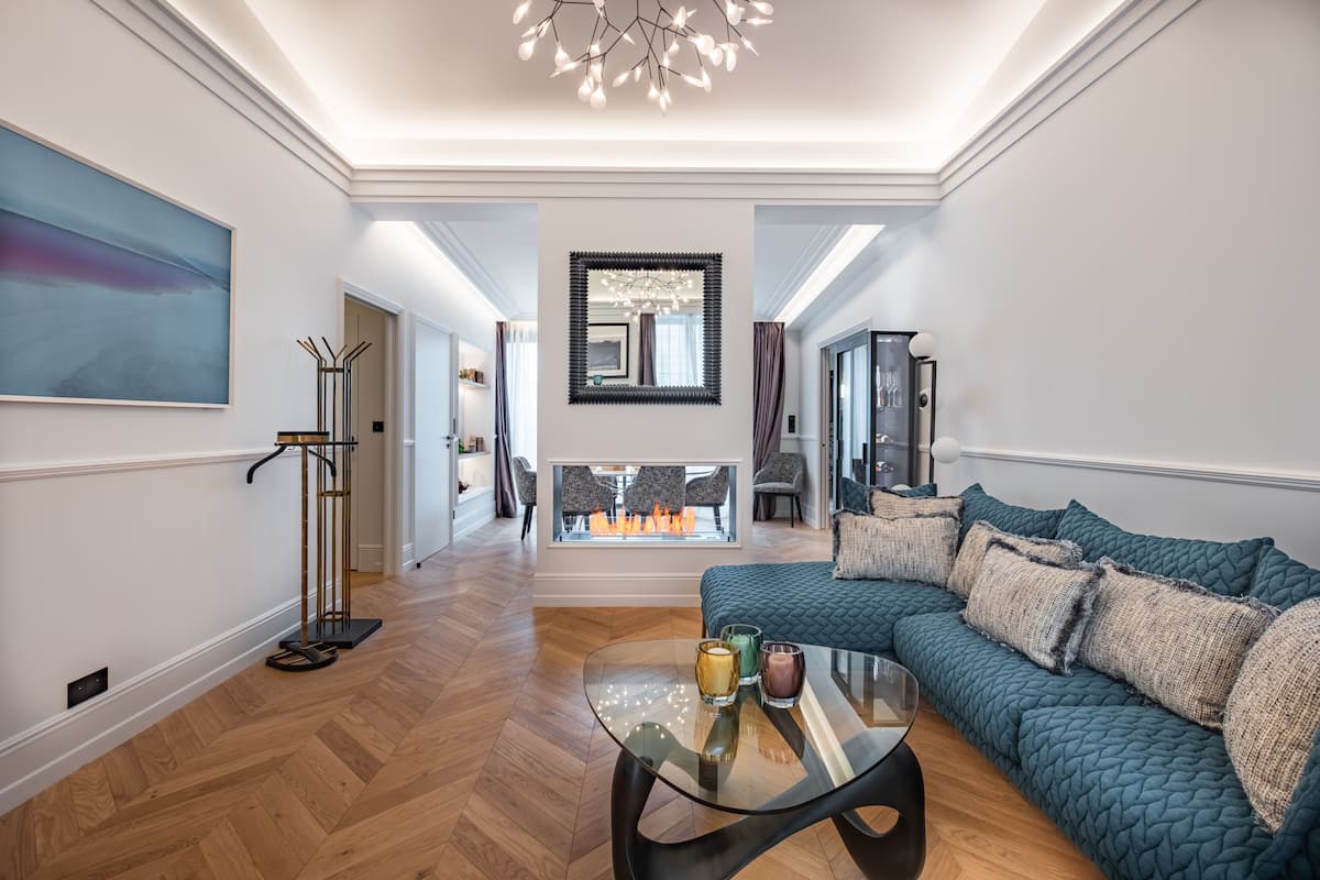 Una sala de estar moderna con un sofá, una mesa de centro de vidrio, una chimenea y un espejo grande.