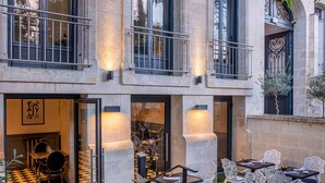 A courtyard with outdoor seating, stone walls, and a glass door entrance. - Le Palais Gallien Hôtel & Spa (Bordeaux)