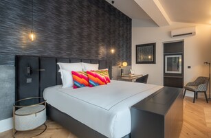 A modern bedroom with a large bed, a bedside table, a chair, and a lamp.