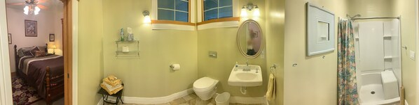A bathroom with a toilet, sink, and shower. There is a mirror above the sink and a window above the toilet. - Spacious ADA accessible Victorian in the Heart of Manitou Springs (Manitou Springs)