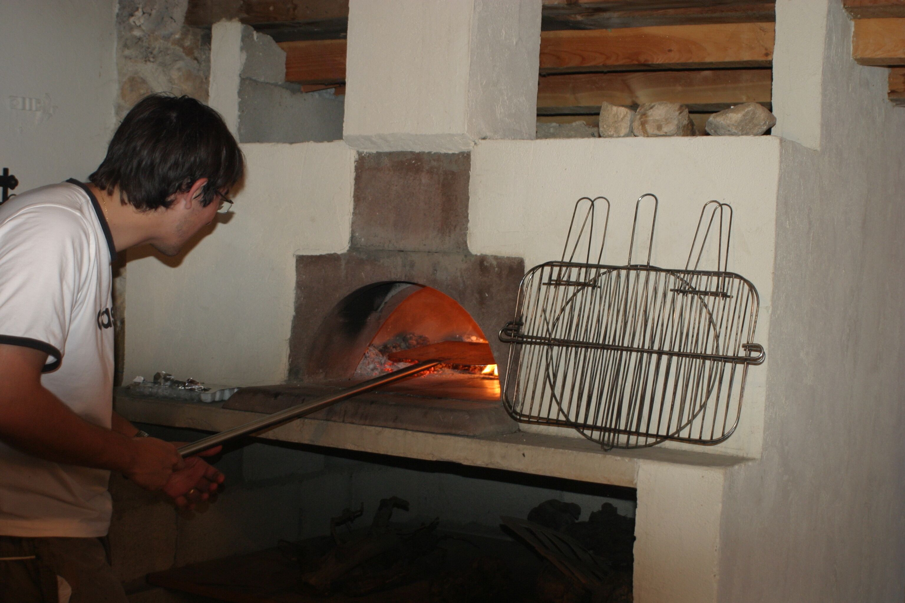 Een persoon gebruikt een lange hendel om een bakoven te bedienen.