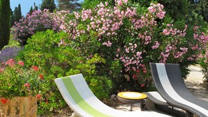 A garden area with two lounge chairs and a small table, surrounded by lush greenery and flowering plants. - Unique in Provence: the Mas Mirabelle in Eygalières (Eygalières)