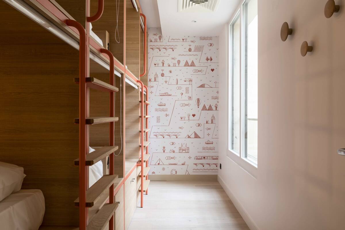 A narrow hallway with a bunk bed on the left and a patterned wall on the right.