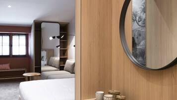 Un dormitorio moderno con una cama grande, un armario de madera, un espejo redondo y una silla de mimbre.