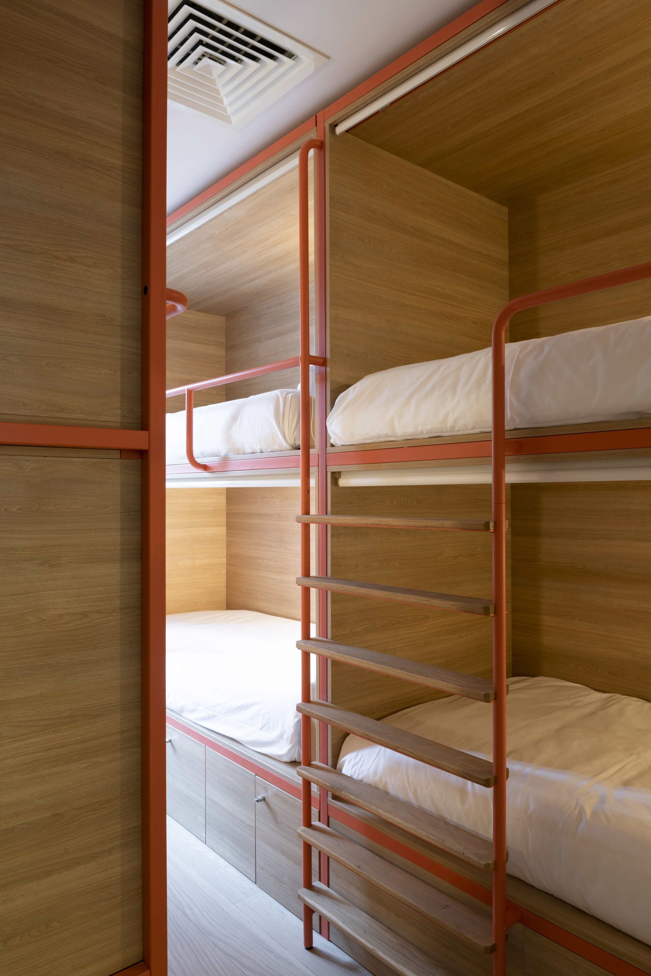Dormitorio con literas, paredes de madera y escalera roja.