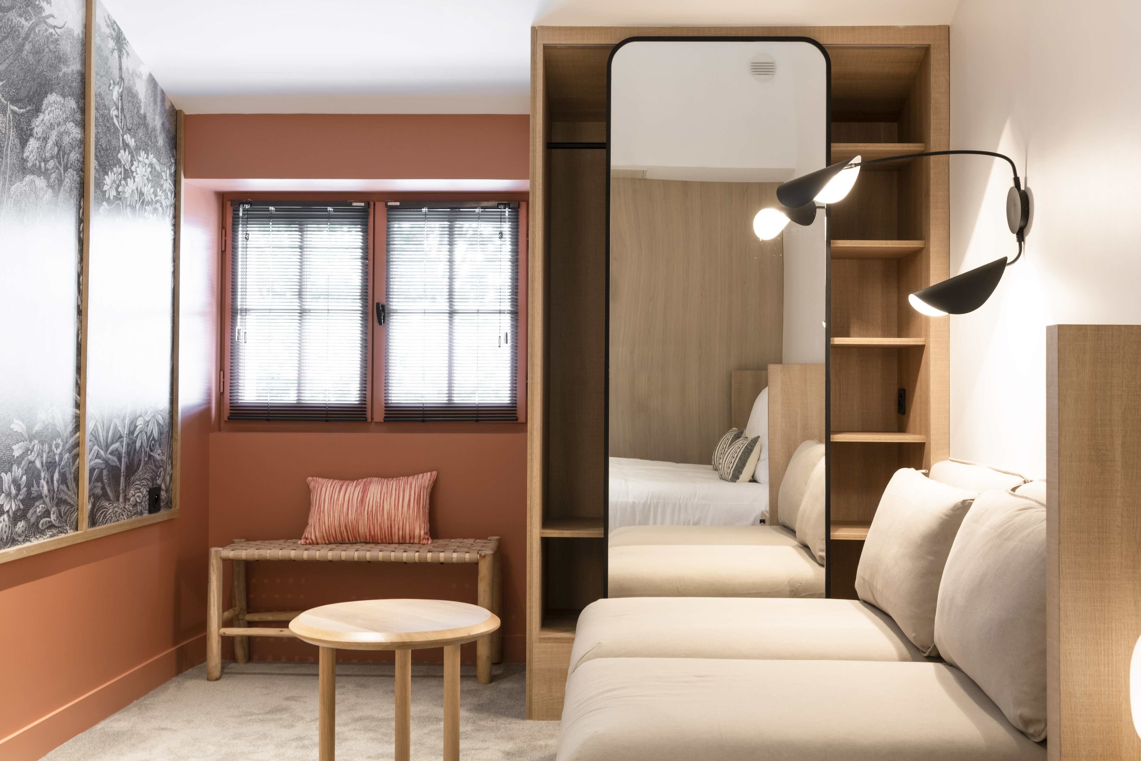 A cozy room with a wooden bench, a round table, a sofa, and a large mirror.