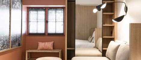 A cozy room with a wooden bench, a round table, a sofa, and a large mirror.
