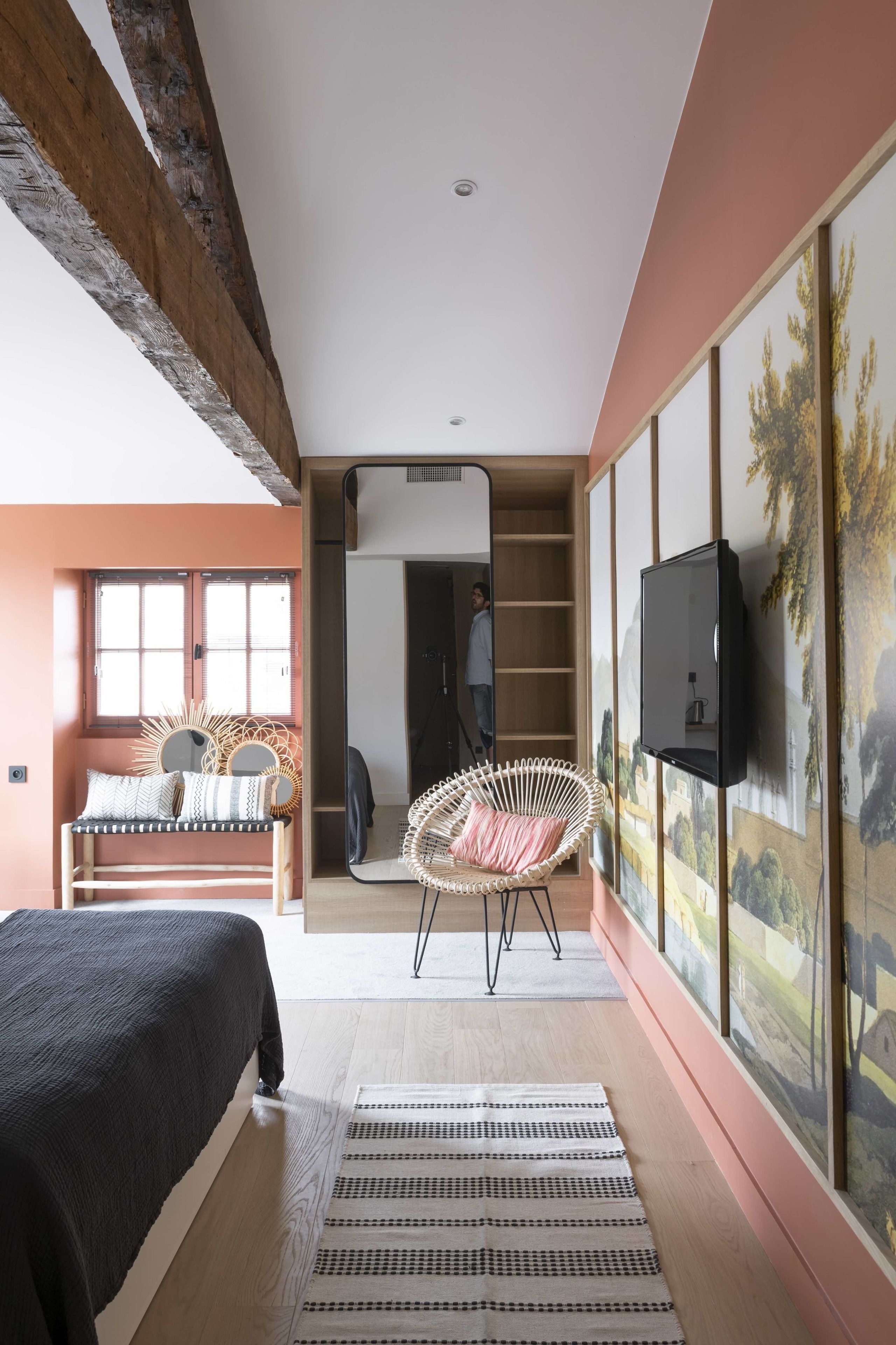 Un dormitorio con cama, sofá, sillón, televisor y un mural.