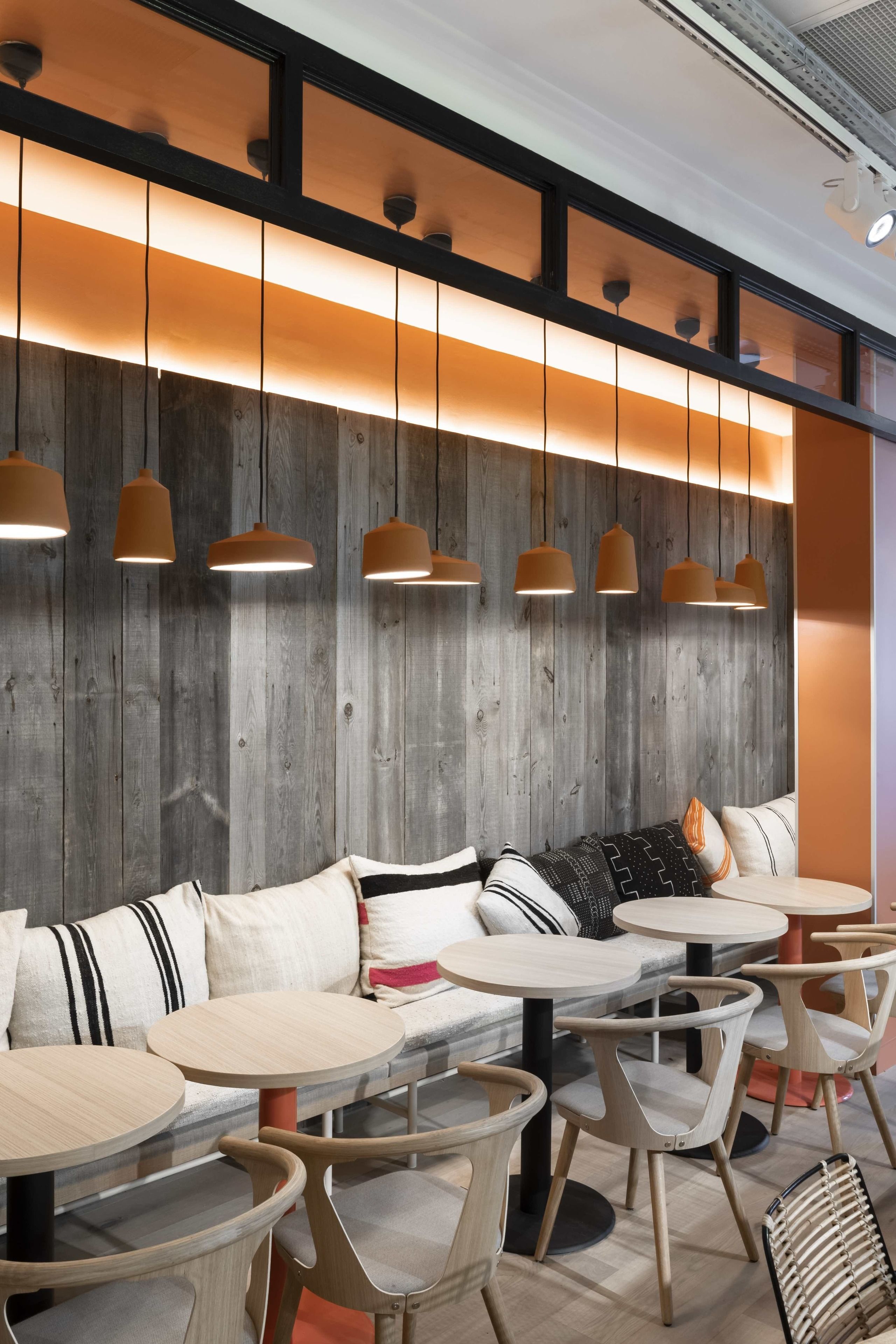 A modern interior with wooden panel walls, round tables, and cushioned seating.