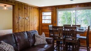 Ein Holzinterieur mit Ledersofa, Esstisch aus Holz und Stühlen.