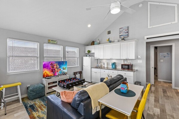 A compact living space with a sofa, TV, kitchenette, and a dining area.
