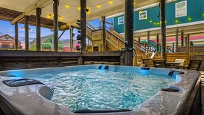 A hot tub area with wooden deck and stairs leading to a building with colorful exterior walls.