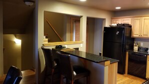 A compact kitchen with a central island, wooden cabinets, and a black refrigerator. - Smashing Location! - Affordable, Max. Amenities, Hot Tub, Views (Big Sky)