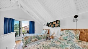 Une chambre avec deux lits, un plafond en bois, une petite table avec une lanterne et une vue sur l’extérieur, visible à travers une porte vitrée.