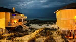 A beachfront property with a wooden structure, a sandy path, and a view of the ocean under a cloudy sky. - Pacifico Destin SPC 2135! An exquisite condo experience right on the beach! (Destin)