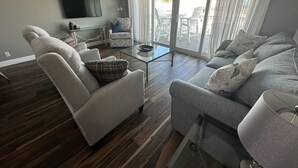 A living room with a sofa, armchair, and a coffee table. - Pacifico Destin SPC 2135! An exquisite condo experience right on the beach! (Destin)