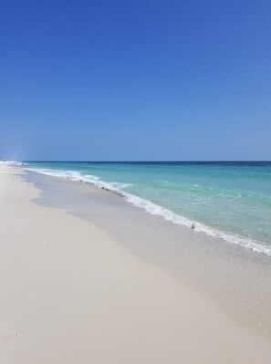 A beach with clear turquoise water and a wide sandy shore.