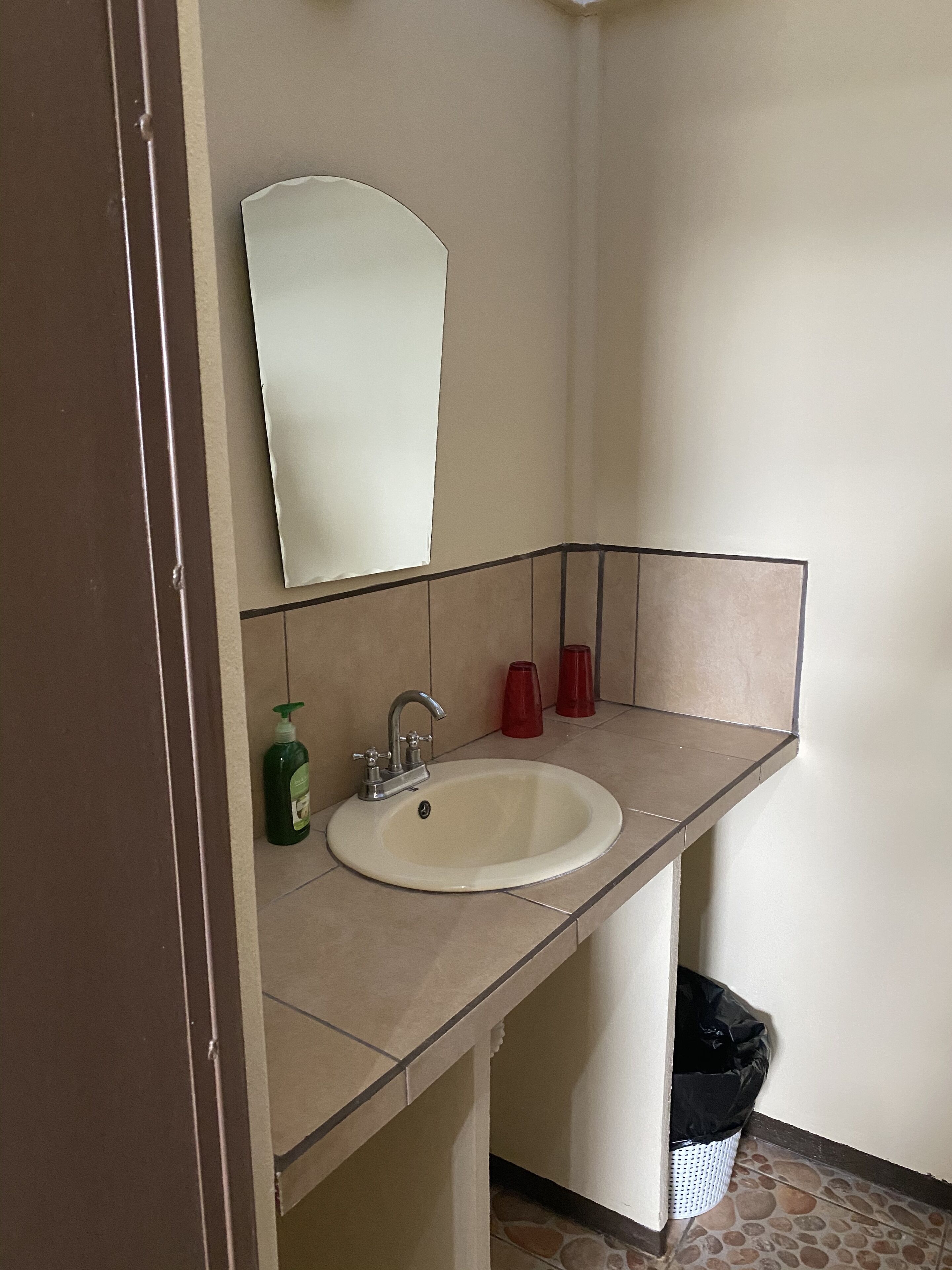 A bathroom with a sink, mirror, and two red cups.