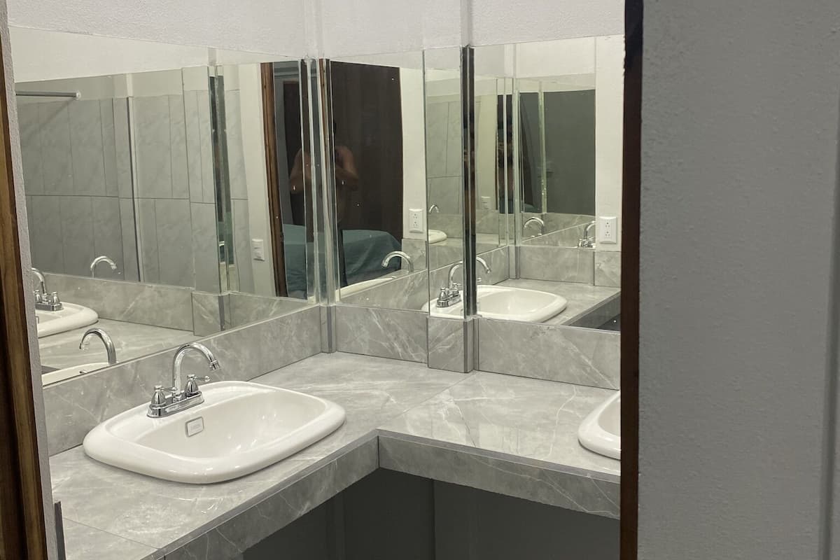 A modern bathroom with two sinks, a large mirror, and a shower area.