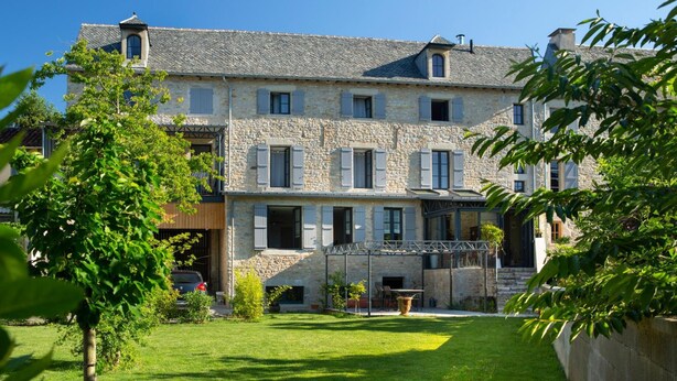 A stone building with multiple windows and a covered outdoor area. - La Maison de Siloe (Villefranche-de-Rouergue)