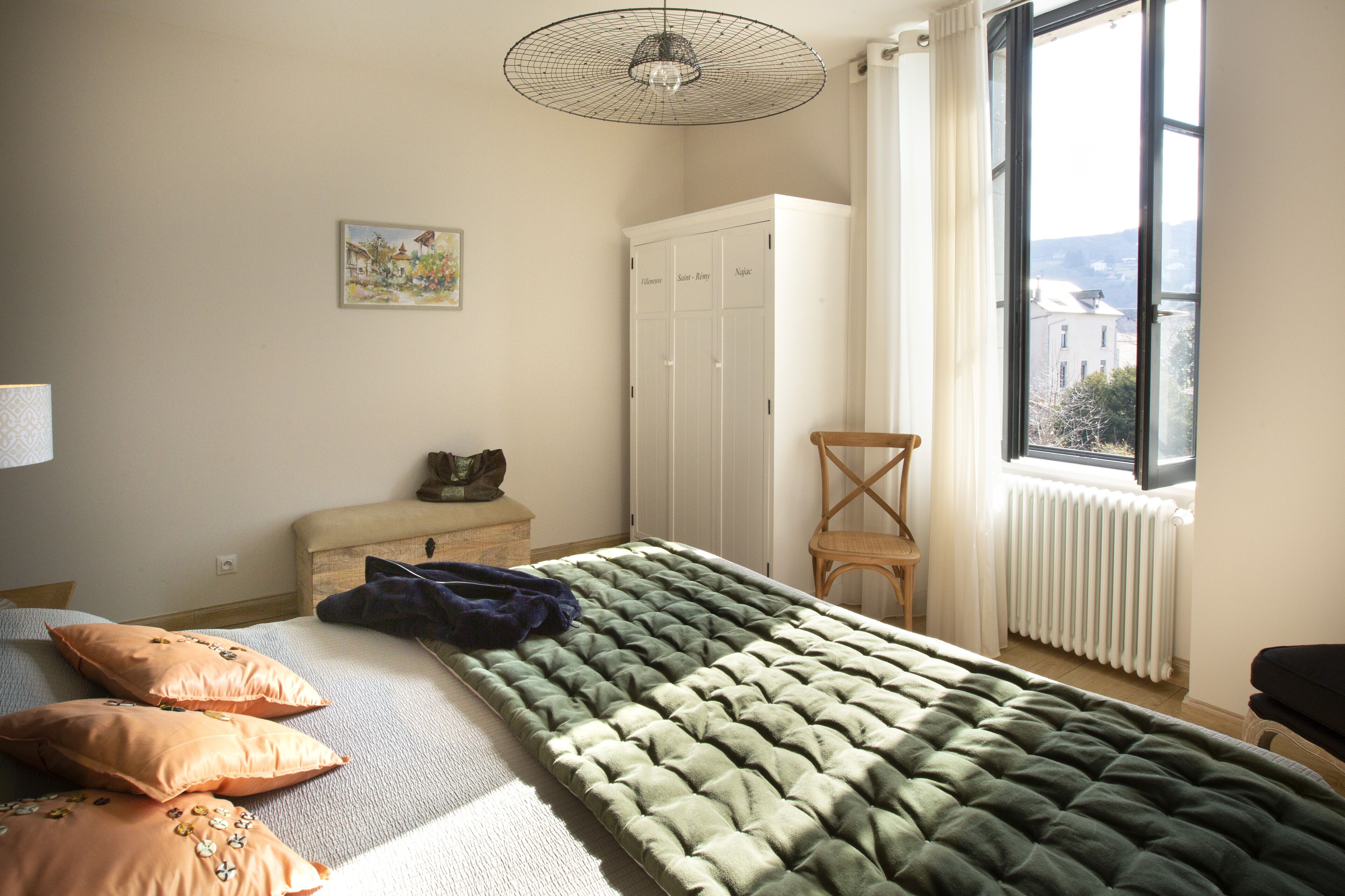 Un dormitorio con cama, cómoda, radiador y ventana con vistas.