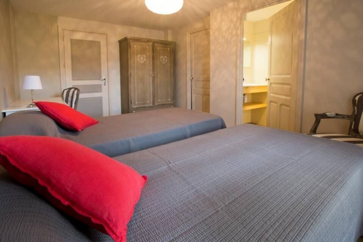 Ein Zimmer mit zwei Betten, einem Kleiderschrank, einem Schreibtisch und einem Stuhl.