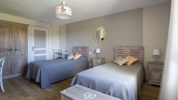 A bedroom with two beds, a wardrobe, a mirror, and a small table.
