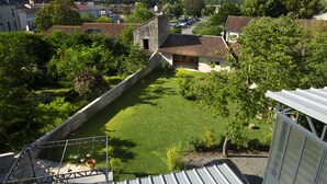 A courtyard with a stone wall, a small pool, and a view of surrounding houses and greenery. - La Maison de Siloe (Villefranche-de-Rouergue)