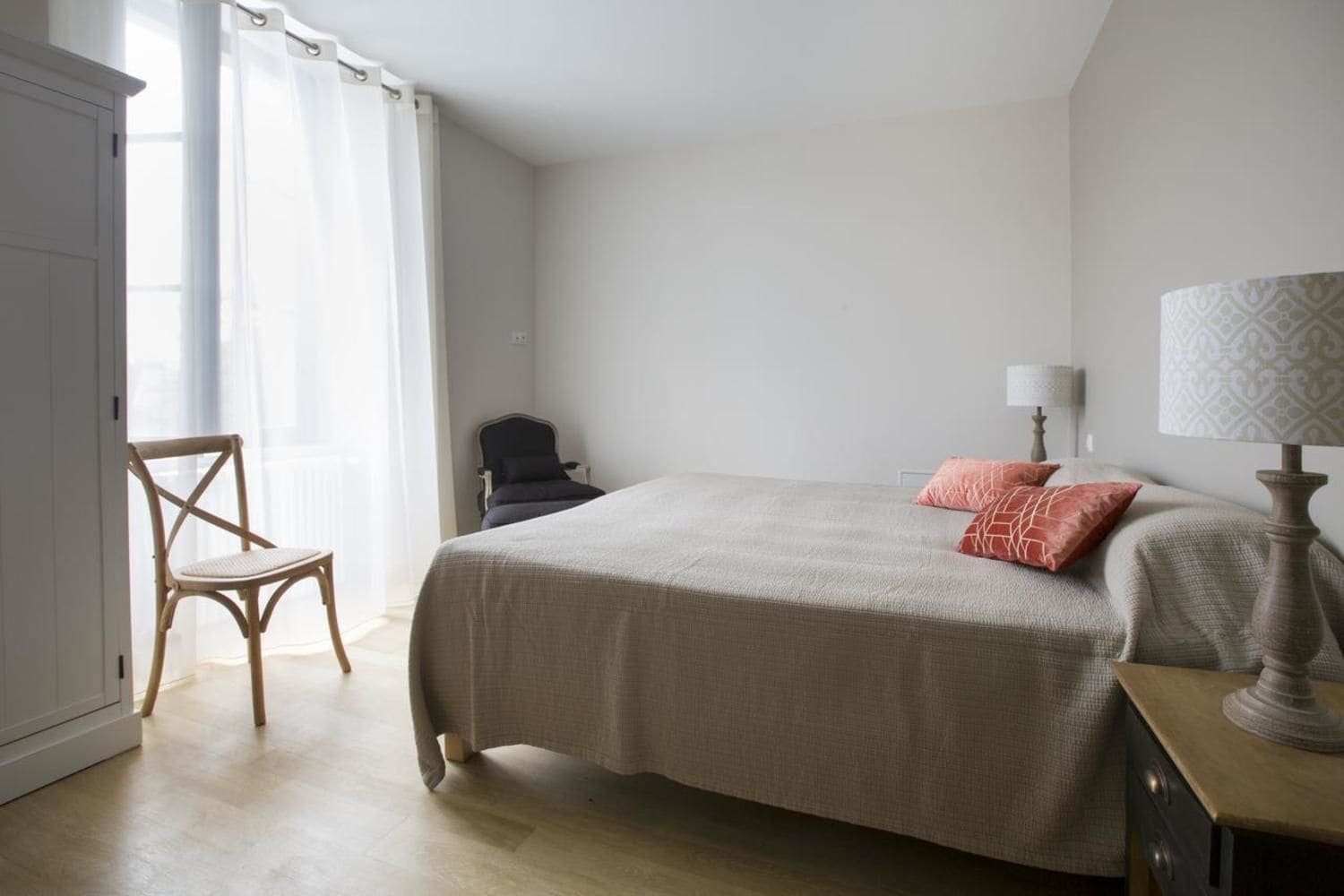 Een slaapkamer met een bed, een stoel, een bureau en een lamp.