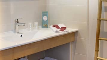 Une salle de bain avec un lavabo blanc, un miroir et un espace pour ranger les serviettes.
