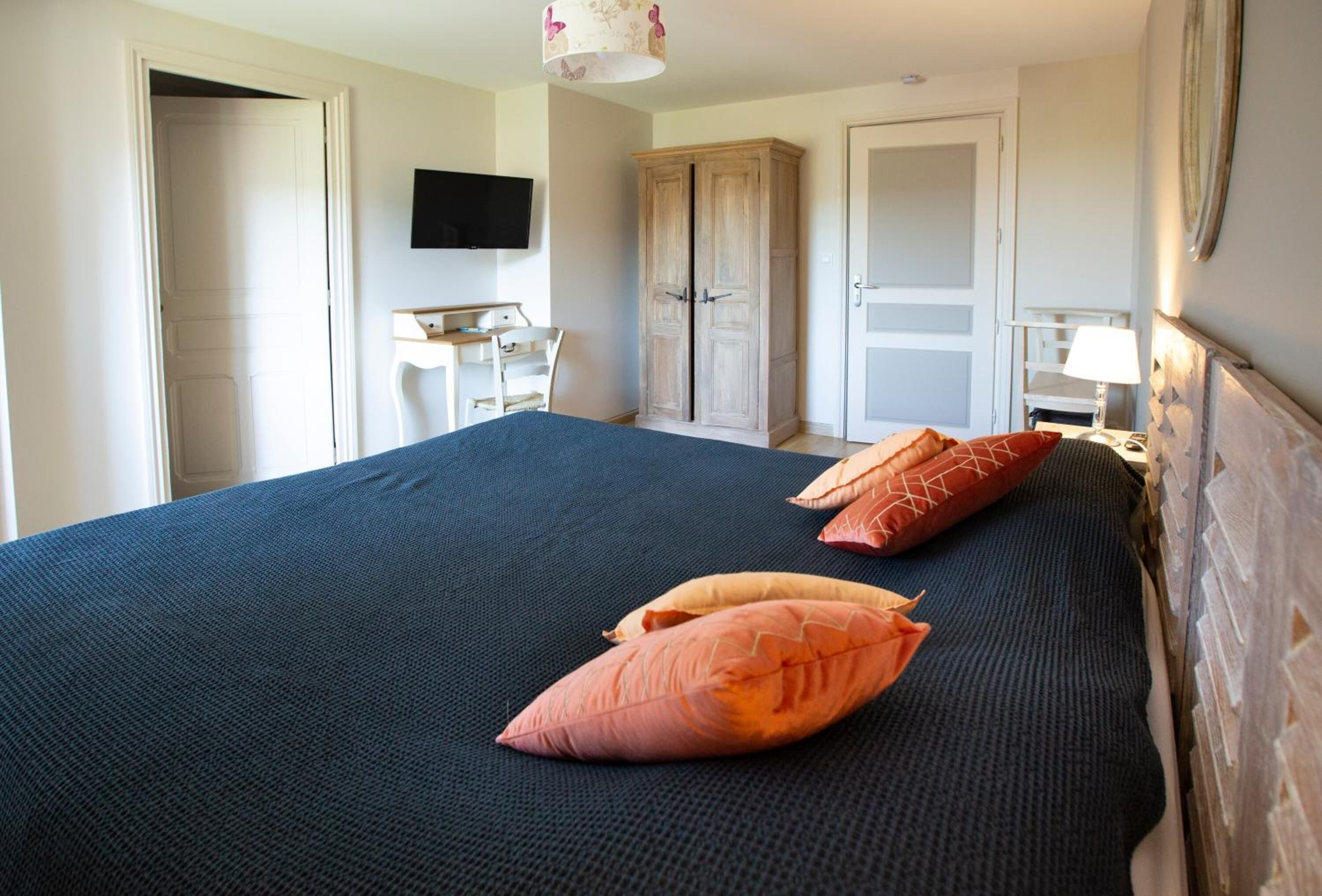 A bedroom with a bed, a desk, and a wardrobe.