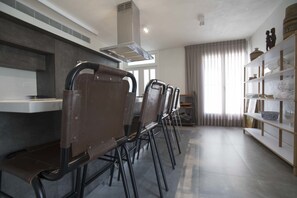 Een moderne keuken met een inbouwfornuis, een eethoek met stoelen en een plank met decoratieve objecten.