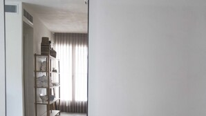 A room with a large mirror reflecting a hallway with a wooden shelf unit and a small black table. - Sasson & Co Luxury apartment Neve Tsedek (Tel Aviv)