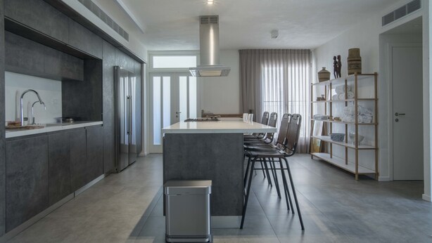 A modern kitchen with a central island, stainless steel appliances, and a dining area with chairs. - Sasson & Co Luxury apartment Neve Tsedek (Tel Aviv)