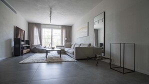 A modern living room with a sofa, coffee table, and a flat-screen TV. - Sasson & Co Luxury apartment Neve Tsedek (Tel Aviv)