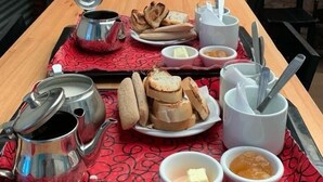 A wooden table with a tray of food, including bread, butter, and jam, and a teapot. - Hotel La Barca (Buenos Aires)